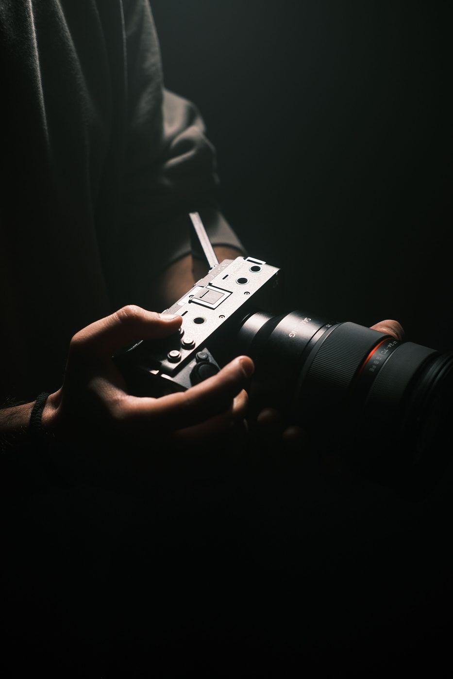 Hands holding a cinema camera in the dark
